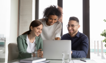 Group of three people looking at a laptop.